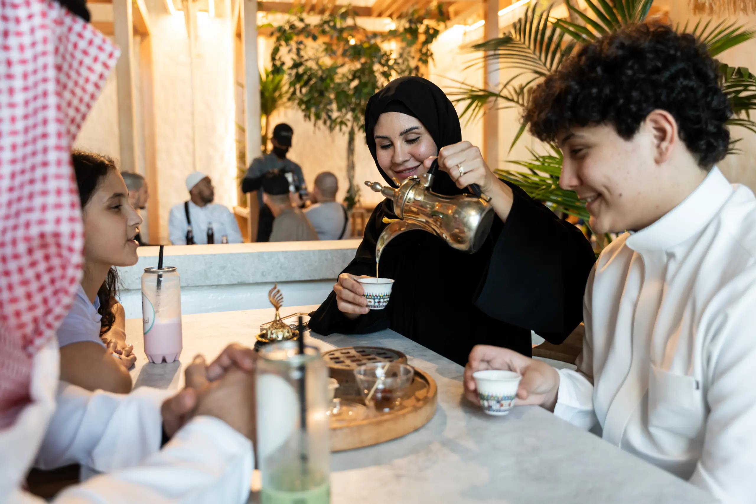 A family sharing traditional coffee at a restaurant in Makkah